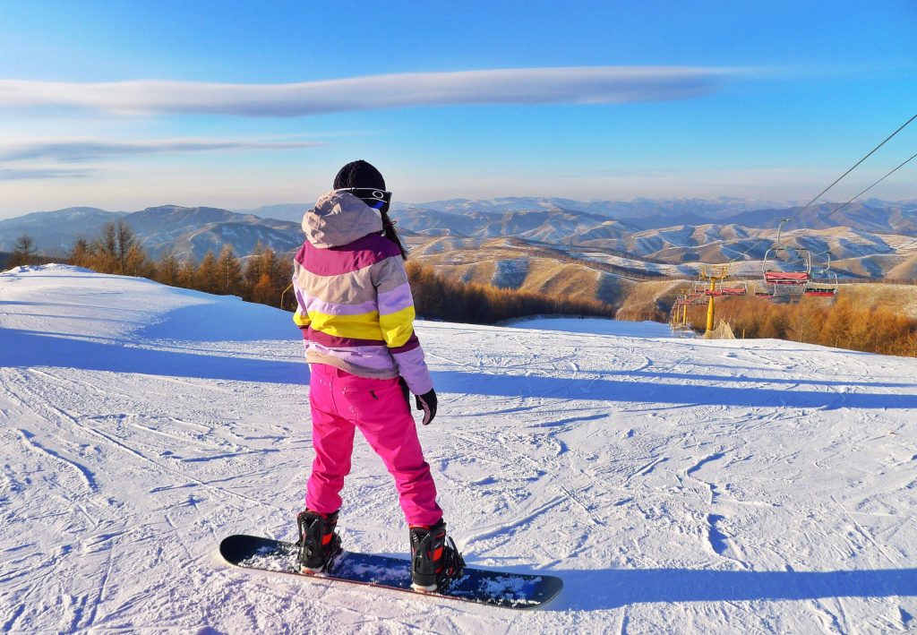 Jeune femme qui profite de ses vacances au ski pour admirer le paysage de montagne