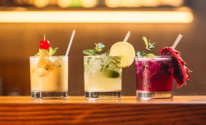 Trois cocktails aux fruits colorés sur un comptoir en bois