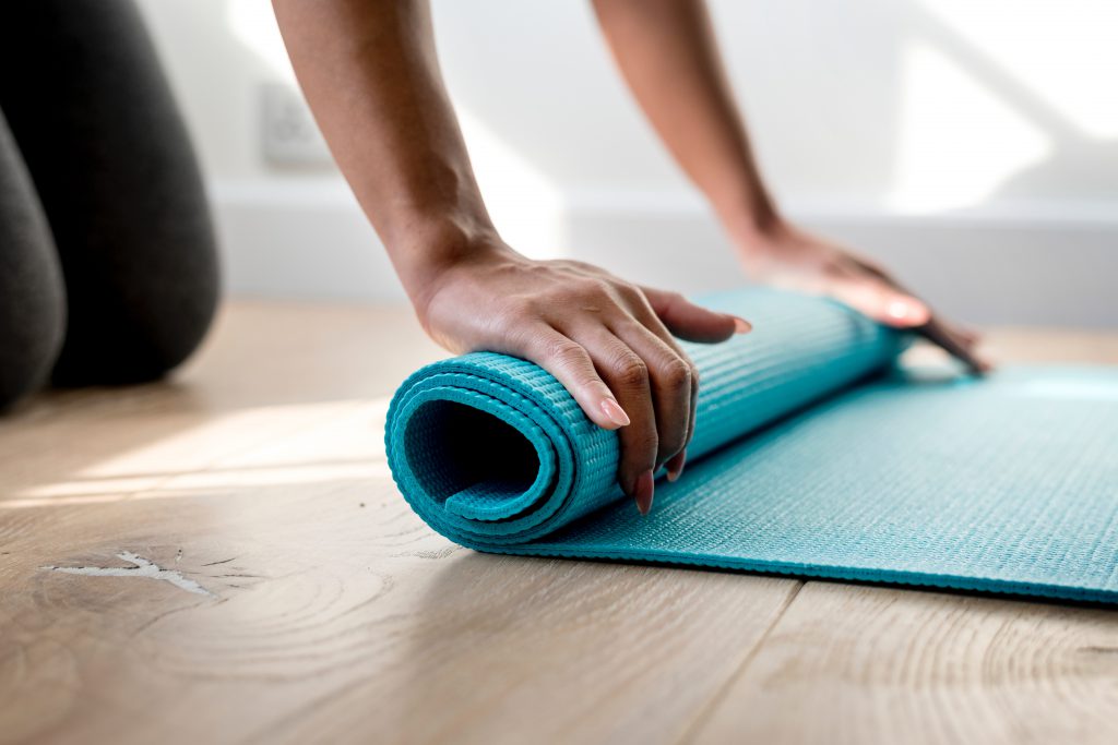 Femme qui roule son tapis de sport au sol