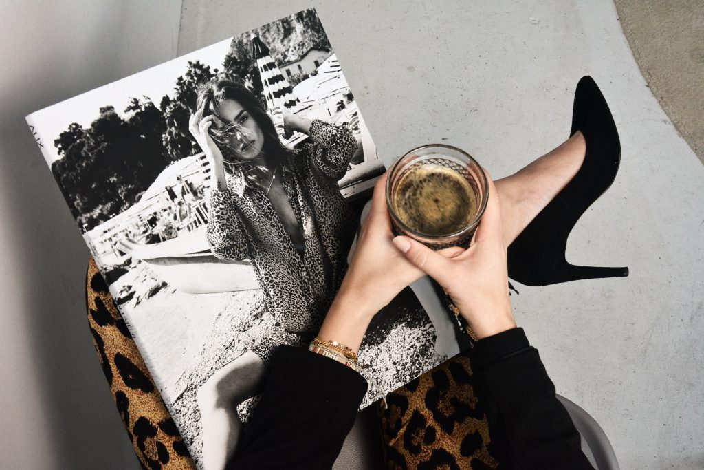 Femme qui croise ses jambes avec des talons aiguilles et une tasse de café dans la main