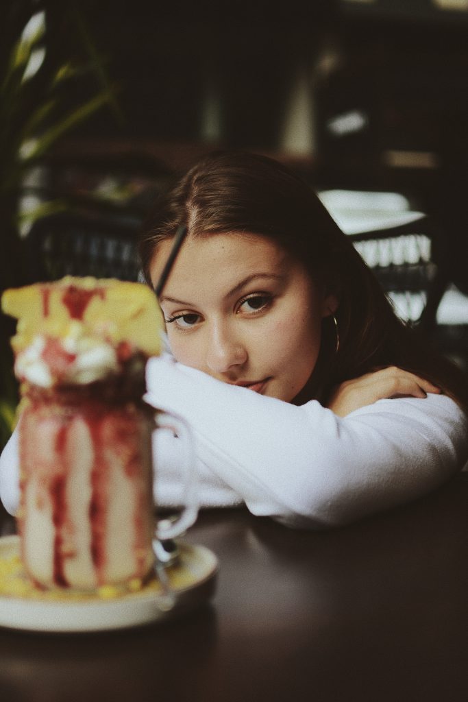 Femme qui met sa tête entre ses bras dans un bar et fixe la caméra