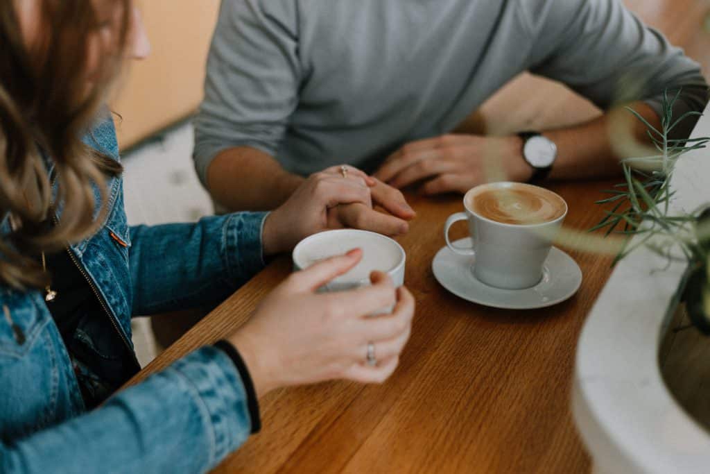 Femme qui tient la main d'un homme lors d'un rendez-vous dans un café