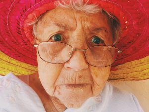 Vieille femme avec chapeau de plage rouge et lunettes