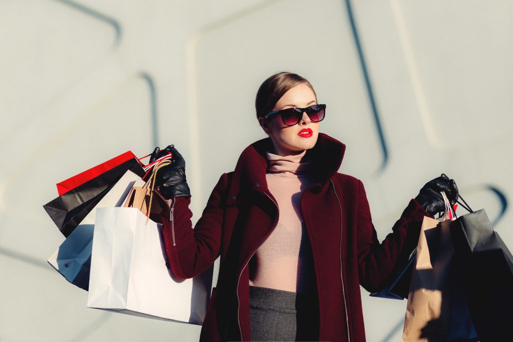 Femme bien apprêtée qui tient plusieurs sacs de shopping dans ses mains