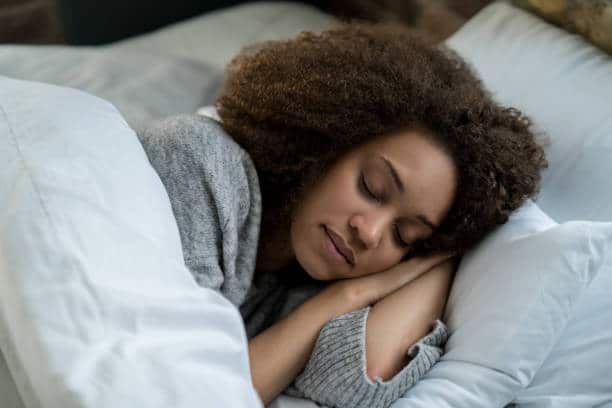 Femme en train de dormir dans son lit au matelas propre