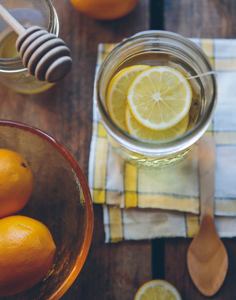 Table avec verre de jus de citron, pot de miel et bol d'oranges