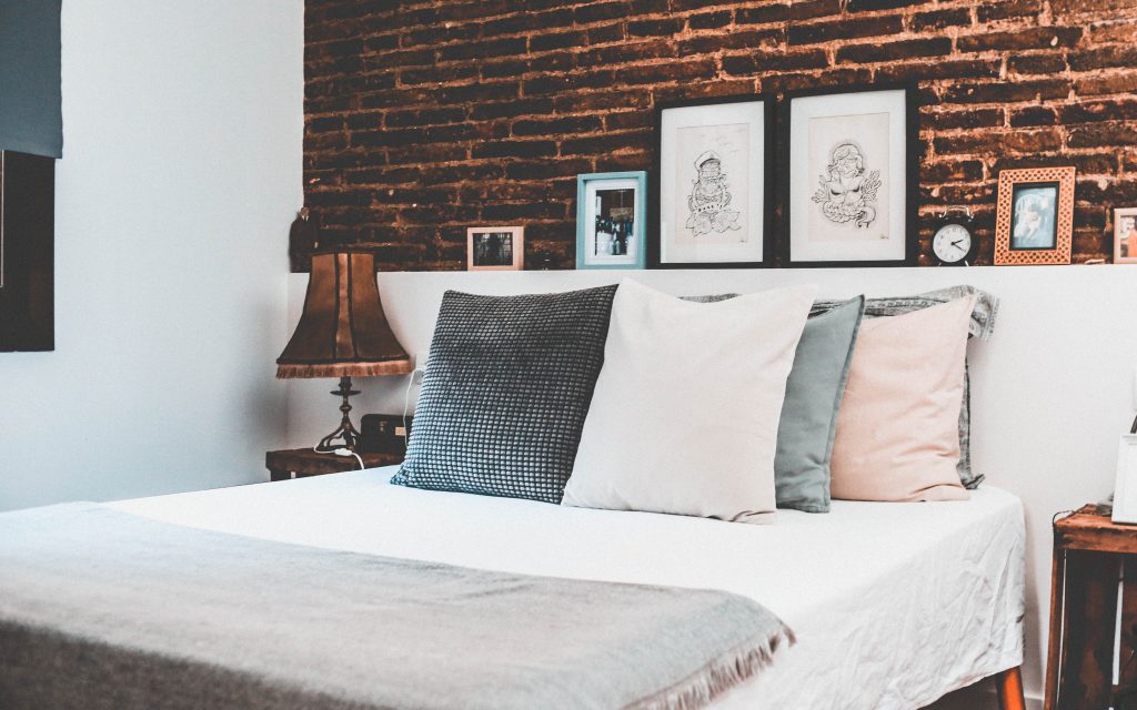 Lit au matelas nettoyé avec jolis coussins et chambre décorée