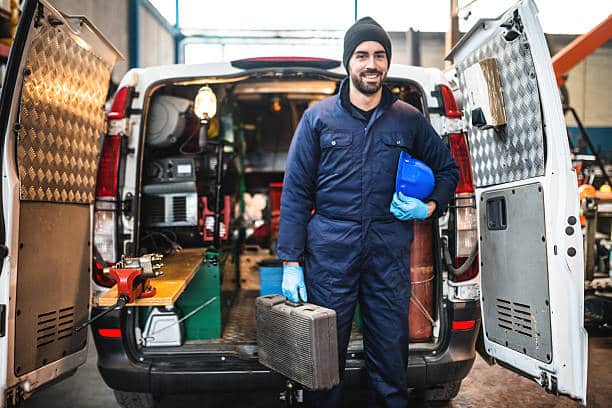 Plombier devant sa camionnette avec tous ses outils et son matériel de plomberie