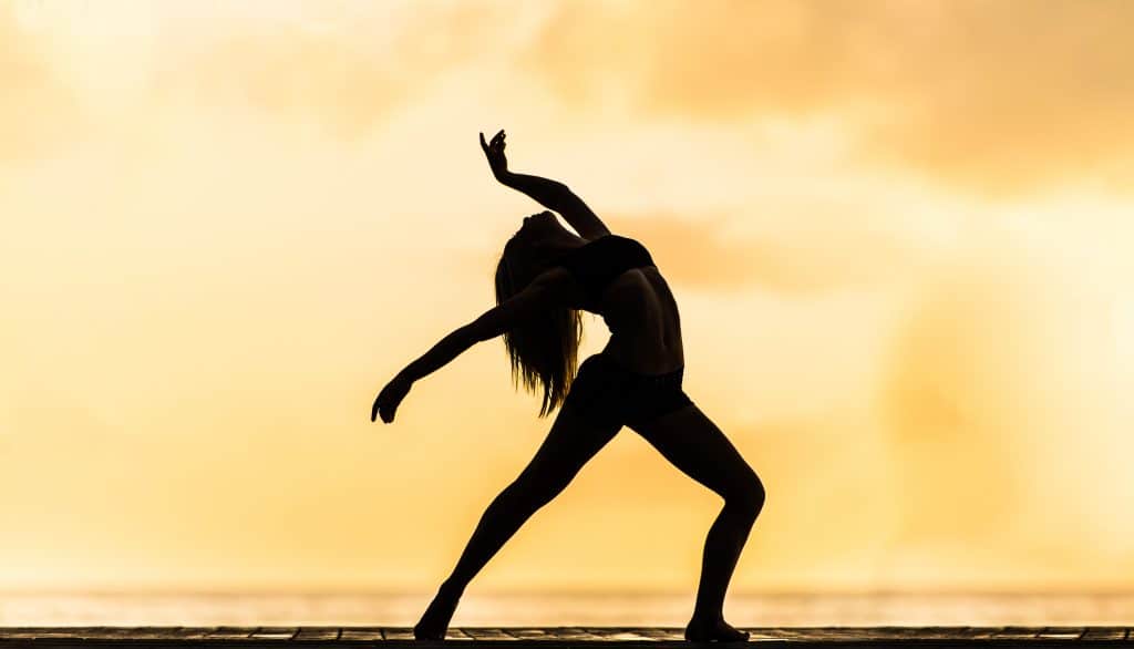 Silhouette d'une femme qui fait du hatha yoga sur ciel orangé