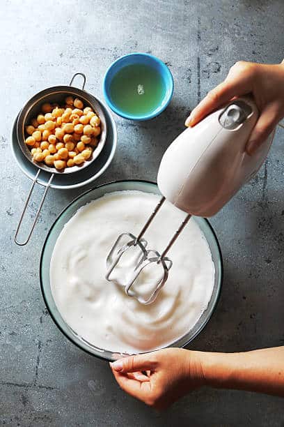 Personne en train de battre des blancs en neige grâce à du jus de pois chiche