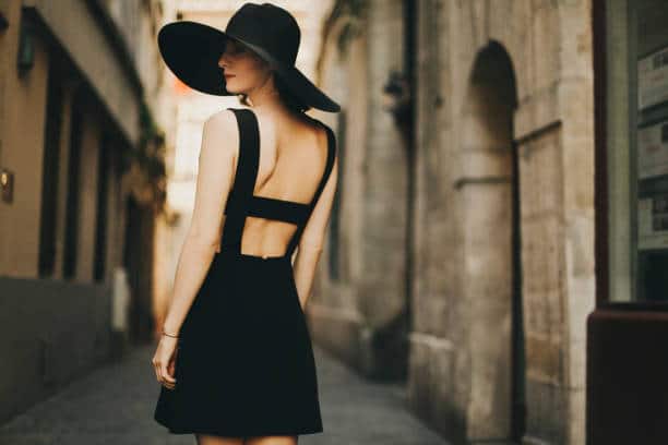 Femme de dos avec robe noire ouverte et chapeau