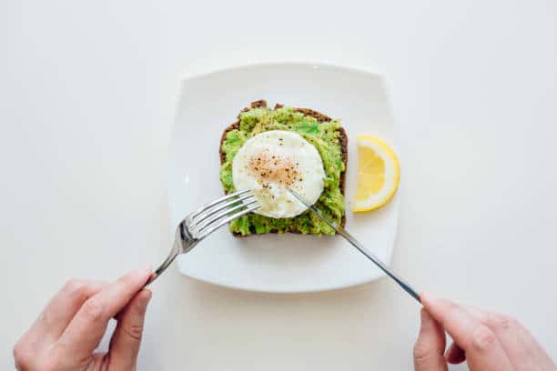 Toast avec un oeuf et du guacamole dans une petite assiette blanche