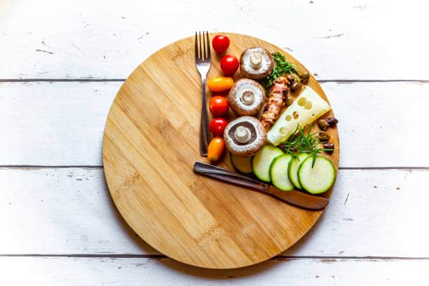 Petite portion de fruits et légumes dans une assiette en bois