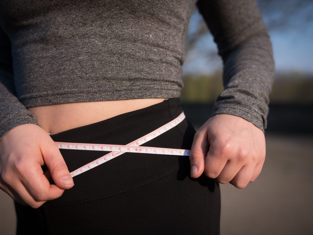 Gros plan sur la taille d'une femme qui calcule son poids à l'aide d'un ruban