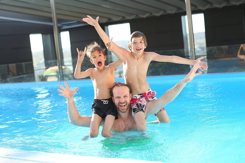 Père de famille qui se baigne avec ses deux fils dans sa piscine