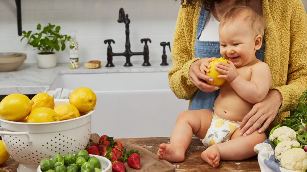 Bébé qui découvre de nouveaux aliments et qui joue avec un citron