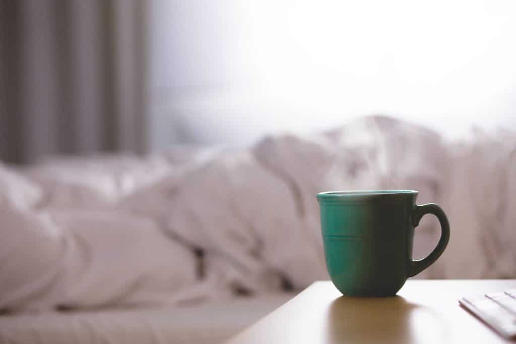 tasse à café posée à côté d'un lit