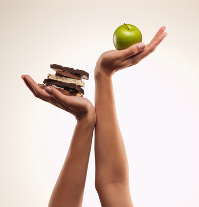 Une pomme verte dans la main droite et du chocolat dans la main gauche