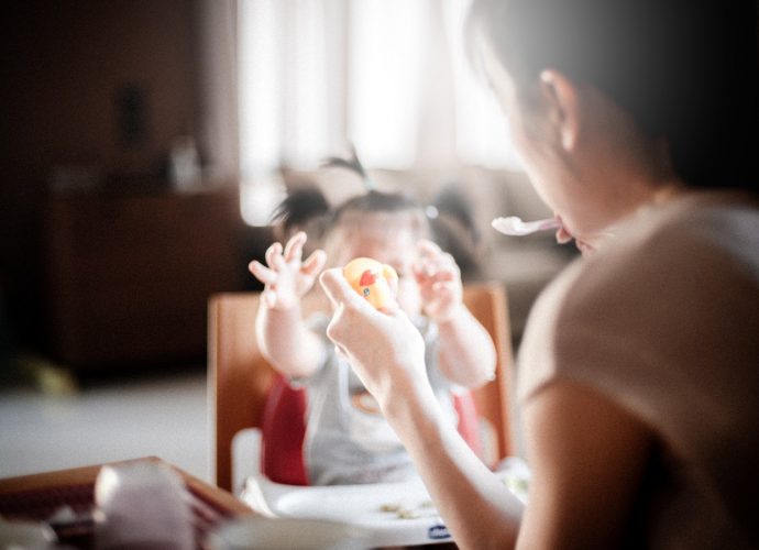 Jeune maman qui donne le repas à son bébé dans une chaise haute