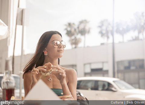 Femme avec des lunettes de soleil mangeant un sandwich