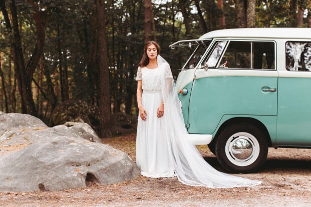 Femme en robe de mariée devant une voiture