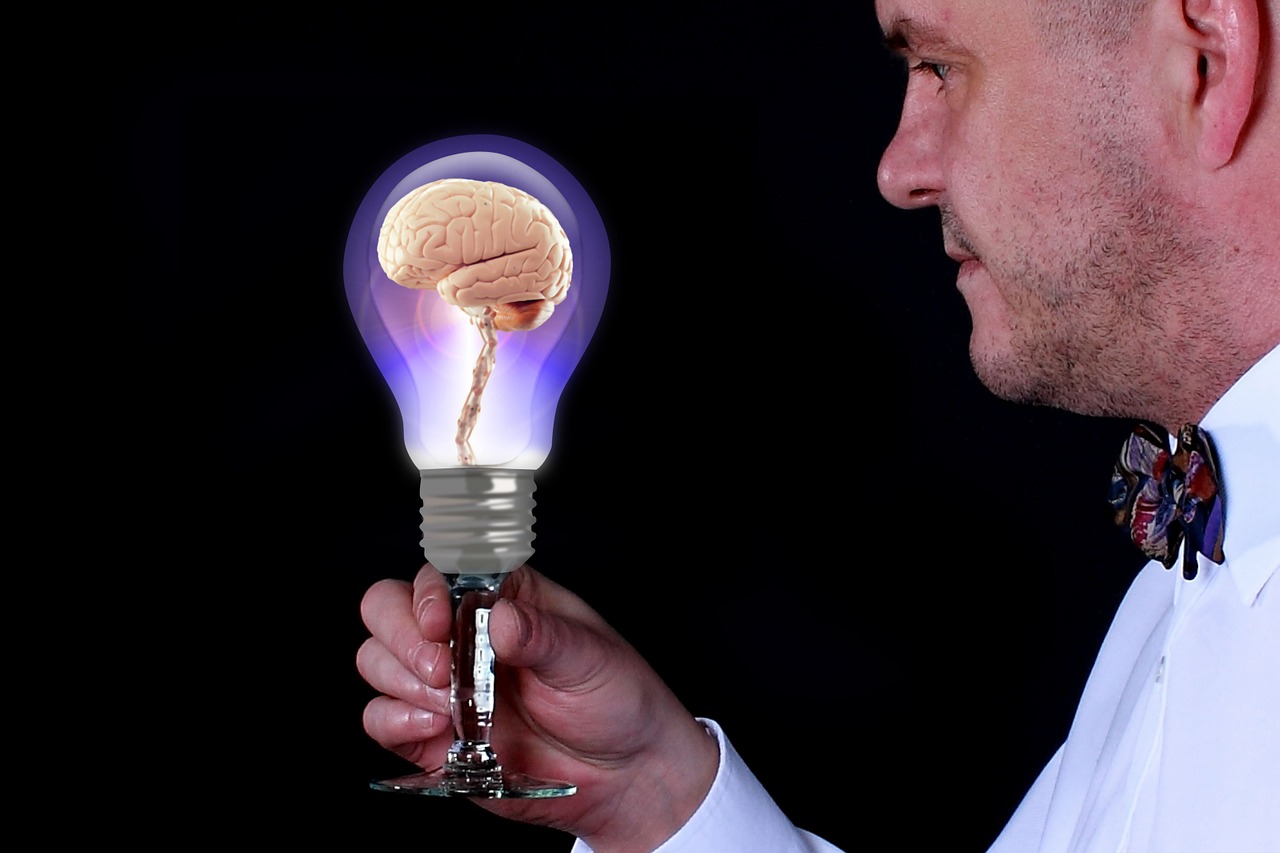 Homme tenant une ampoule avec un cerveau à l'intérieur