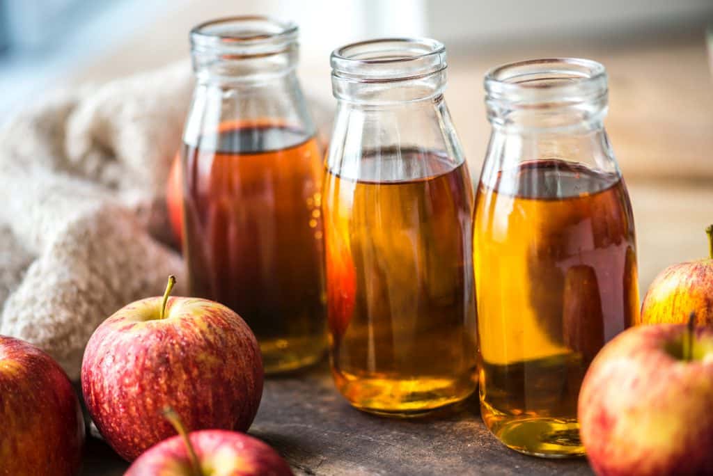 Bouteilles de vinaigre de cidre avec des pommes autour