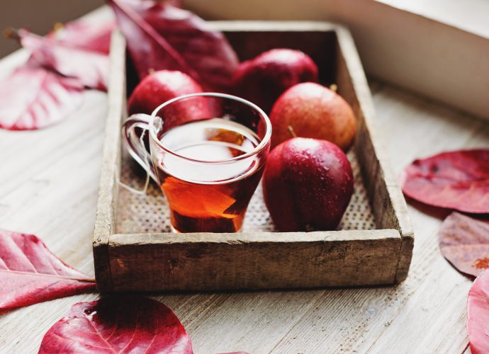 Plateau en bois avec verre de cidre et pommes rouges