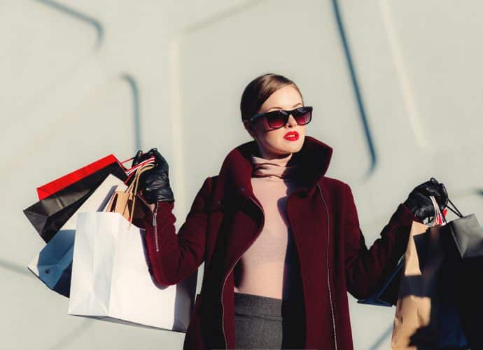 Femme bien apprêtée qui tient plusieurs sacs de shopping dans ses mains