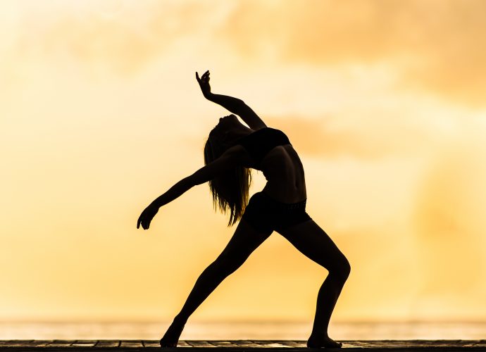 Silhouette d'une femme qui fait du hatha yoga sur ciel orangé